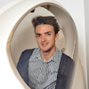 Nicholas poses for a photo in the bod pod, an enclosed white oval with a glass window.