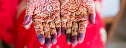 A person holds out their hands to show intricate henna designs on their palms.