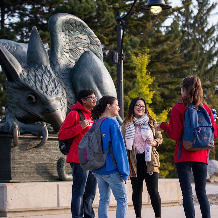 University of Guelph students standing in front of the gryphon statue