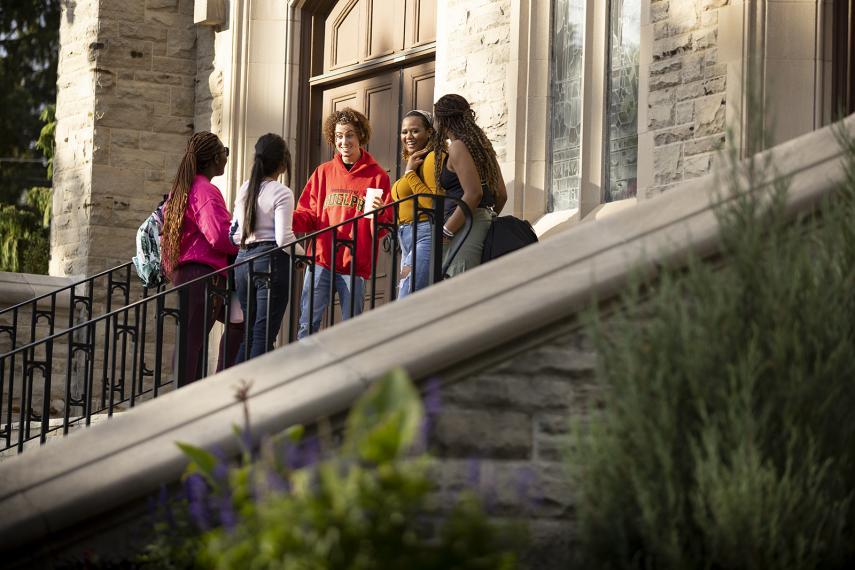 Five students congregate on the steps of War Memorial Hall at the University of Guelph.